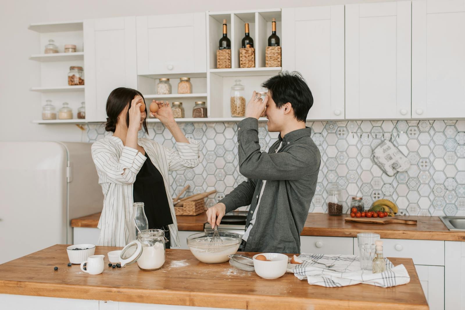 Playful couple baking together in a stylish kitchen, sharing a lighthearted cooking moment.